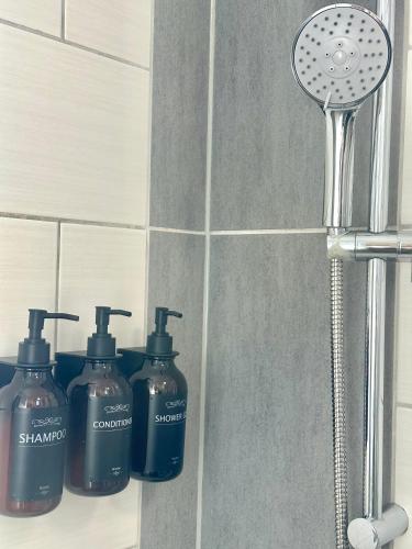 three bottles of shampoo and a shower head in a bathroom at Apartment Alana in Hannover