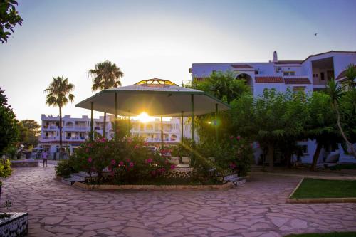 a large umbrella in a courtyard in front of a building at Apartments Kione Playa Romana Park in Alcossebre