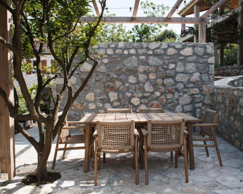 a wooden table with chairs and a stone wall at Galathea House in Kotor