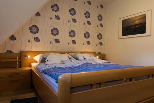 ein Schlafzimmer mit einem Bett mit blauer Bettwäsche und einer Blumenwand in der Unterkunft Friesenhof Jöns in Garding