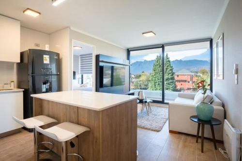 a kitchen and living room with a large window at Vista Pucón 2D2B con vista al Volcán in Pucón