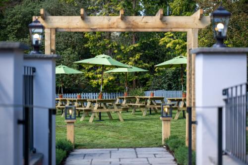a wooden pergola with picnic tables and umbrellas at Himley House by Chef & Brewer Collection in Himley