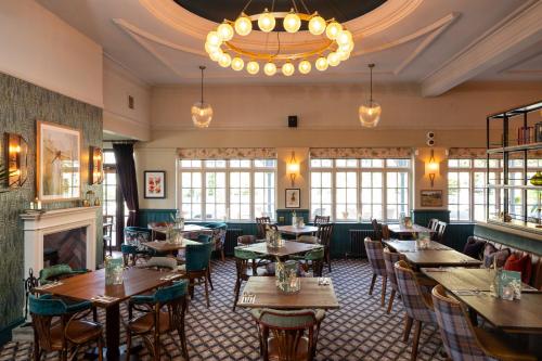 a restaurant with tables and chairs and a chandelier at Himley House by Chef & Brewer Collection in Himley