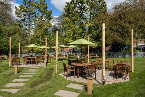 a group of tables and chairs with umbrellas at Himley House by Chef & Brewer Collection in Himley
