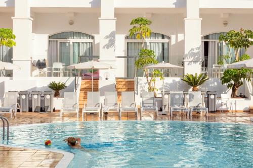 a dog swimming in the pool at a hotel at Sunwing Fañabe Beach in Adeje