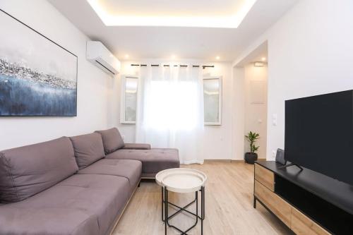 a living room with a couch and a flat screen tv at Venetian Canvas Retreat in Corfu