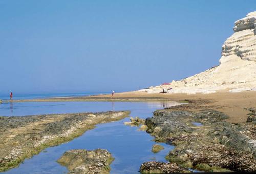 a beach with rocks and people walking on the beach at Azienda Agricola Mandranova in Palma di Montechiaro