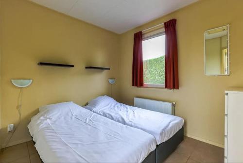ein Schlafzimmer mit einem weißen Bett und einem Fenster in der Unterkunft Chalet de Vlotvaren in Wervershoof