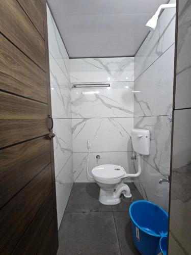 a bathroom with a toilet and a blue bucket at LOWFARE HOTELS in Kozhikode
