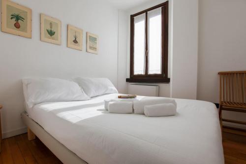 a white bed in a white room with a window at HACCA Collection - Brera & Fashion District - Bright 2BR Apt in Milan
