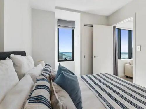 1 dormitorio con 1 cama y algunas almohadas en Sky Tower Views 2 Bed 2 Bath CBD Zodiak Stays, en Auckland