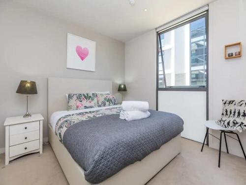 a white bedroom with a bed and a window at Wynyard Viaduct Habour 2 brm 2 bath and carpark in Auckland