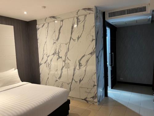 - une chambre avec un lit et un mur en marbre dans l'établissement Sky dome resotel, à Bangkok