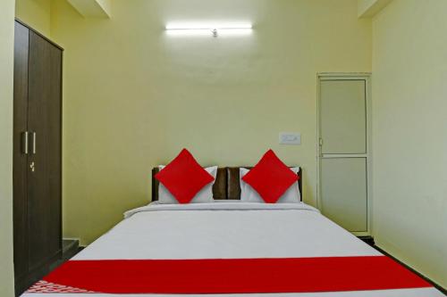 OYO Flagship Sri Chamundeshwari Boarding And Lodge في بانغالور: غرفة نوم بسرير كبير ومخدات حمراء