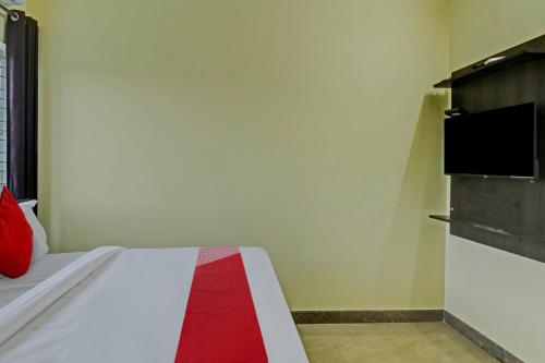 1 dormitorio con 1 cama y TV en la pared en OYO Flagship Sri Chamundeshwari Boarding And Lodge, en Bangalore