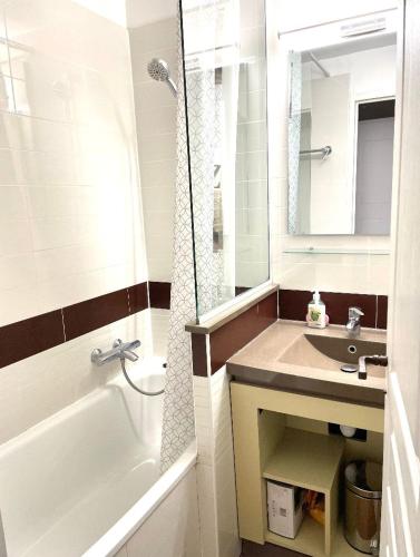 une salle de bain avec une baignoire, un lavabo et un miroir dans l'établissement Appartement village Cap-Esterel - Agay - Saint-Raphaël, à Agay
