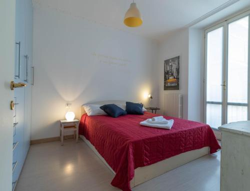 a white bedroom with a bed with a red blanket at Lovely Home Apartment in Lecco