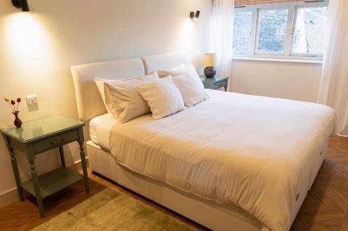 a bed with white sheets and pillows and a table at Amarelo apartment, Central Charlbury, 1 Super king bed in Charlbury