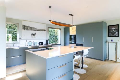 a kitchen with blue cabinets and a white counter top at Villa - Piscine - Spa - Vue imprenable - Terrasse in Baden