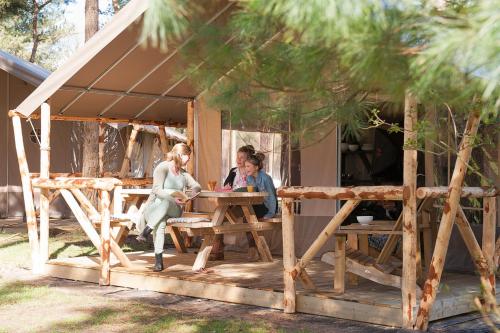 Três mulheres sentadas numa mesa de piquenique num barracão. em Safaritent em Alphen