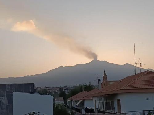 a mountain in the distance with smoke in the sky at Attico in città con terrazza vista etna mare in Acireale