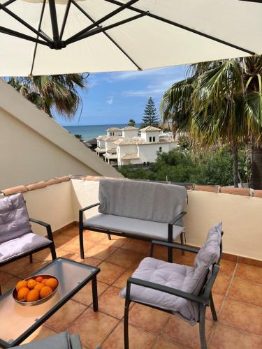 een patio met 2 stoelen, een tafel en een parasol bij STYLISH TOWNHOUSE IN BEACHFRONT COMPLEX in Marbella