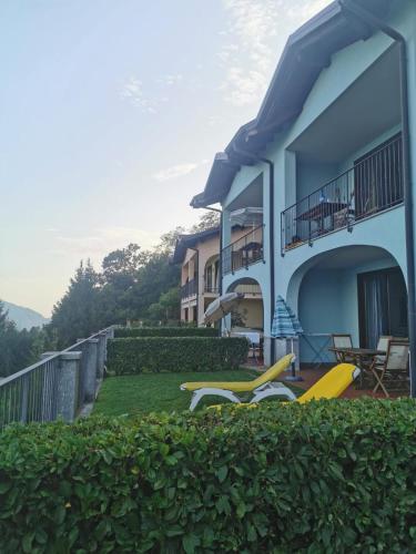 a house with a yard with chairs and a balcony at Residence Il Vigneto in Oggebbio