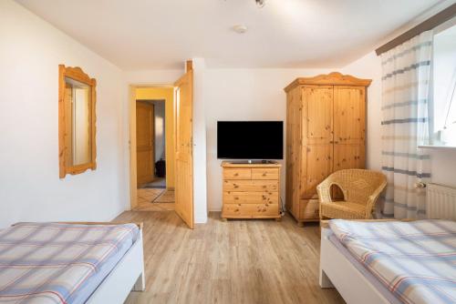 a bedroom with a bed and a tv and a cabinet at Ferienwohnung Krempermoor 1 in Krempermoor