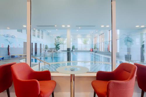 a room with chairs and a table and a swimming pool at McWilliam Park Hotel in Claremorris