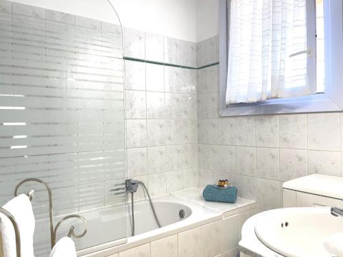 a white bathroom with a tub and a sink at Appartement 2 chambres à 100 m de la plage in Fréjus