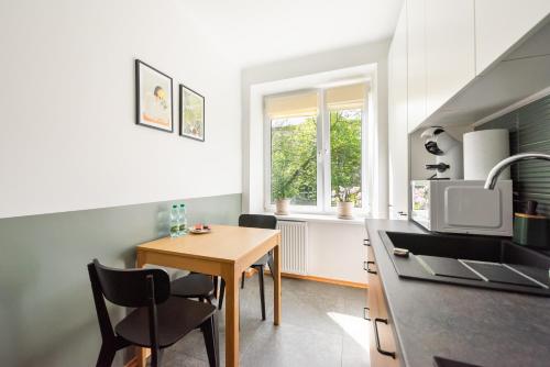 Metro Racławicka Homey Apartment في وارسو: مطبخ مع طاولة وكراسي ومغسلة
