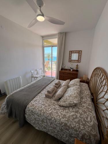 1 dormitorio con 1 cama con ventilador y ventana en Primera línea de playa con preciosas vistas al mar, en Cunit