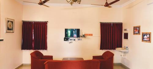 sala de estar con 2 sillas y TV en Black Pepper Cottage Yercaud, en Yercaud