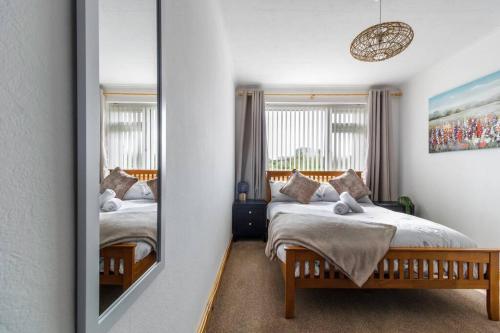 Modest 3 Bed Home, Normanton في نورمانتون: غرفة نوم بسريرين ومرآة