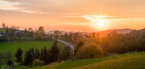 einen Sonnenuntergang über einem grünen Feld mit einer Straße in der Unterkunft Residences Central Winterberg in Winterberg
