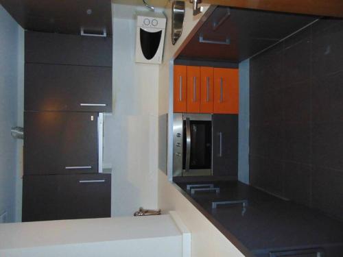 a kitchen with black and orange cabinets and a microwave at Apartamento Bal De Tena in Formigal