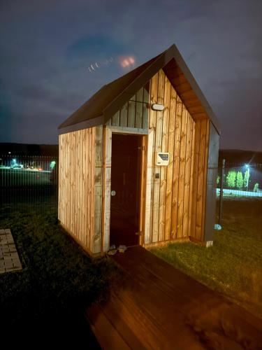 a wooden shed with a door in the grass at Hoszów 28D in Hoszów