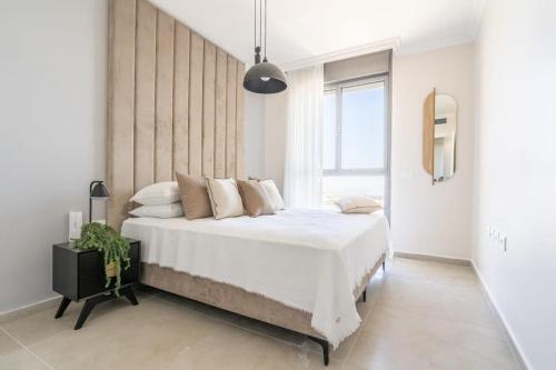 una camera da letto con un letto grande con lenzuola e cuscini bianchi di Savyon View Tower - Isrentals a Gerusalemme