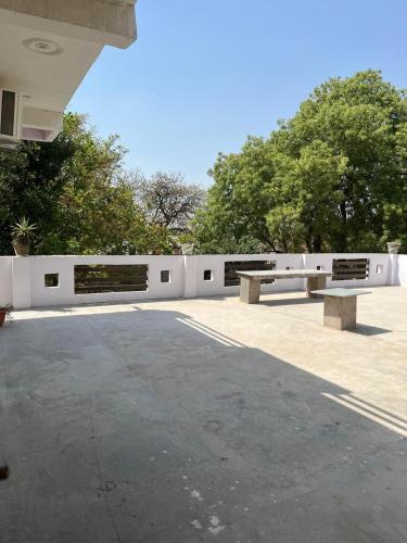 two park benches sitting next to a white fence at Shri SeetaRam Home Stay Near Shri Ram Janmabhoomi Mandir Ayodhya in Ayodhya
