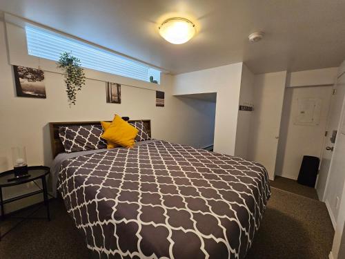 ein Schlafzimmer mit einem schwarzen und weißen Bett mit einem gelben Kissen in der Unterkunft The MJ Tunnel Renovated Suite WiFi Parking in Moose Jaw