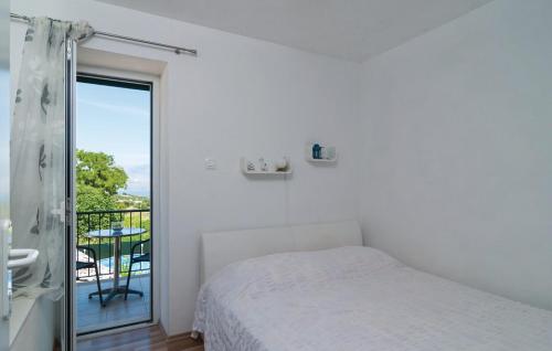 a white bedroom with a bed and a balcony at Holiday Home Marijeta in Škrip