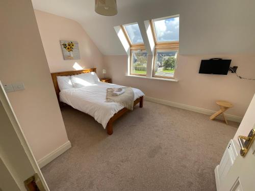 a bedroom with a bed and two windows at Sea Breeze Holiday Home in Enniscrone