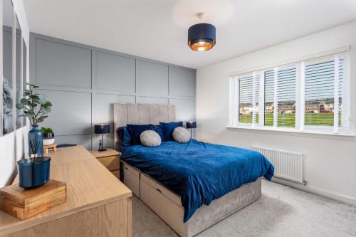 a bedroom with a bed and a desk and windows at 21 Ironfield Lane in Prestwick