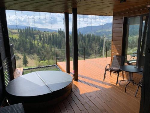 una veranda riparata con tavolo e sedie su una terrazza di Ecottage котедж для двох у горах із чаном-джакузі a Slavske