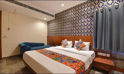 um quarto de hotel com uma cama e uma cortina azul em FabHotel The Wind Palace em Jaipur