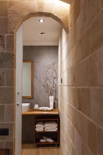 a bathroom with a stone wall and a vanity with towels at Utopia Luxury Suites - Old Town in Rhodes Town