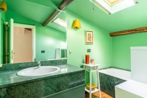 a green bathroom with a sink and a tub at Casa Ginevra - 3 Minutes Walk from the Sea in Livorno