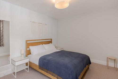 ロンドンにあるThe Oval Abodeのベッドルーム1室(青い毛布、ナイトスタンド付)