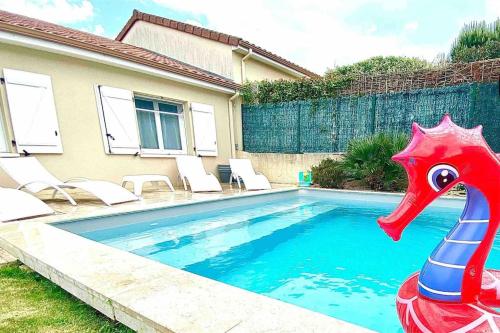 une piscine avec un pélican en plastique devant une maison dans l'établissement La Balneaire maison de standing tout confort, à Boisseuil