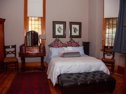 a bedroom with a large bed with a black ottoman at De Avond Rust in Oudtshoorn